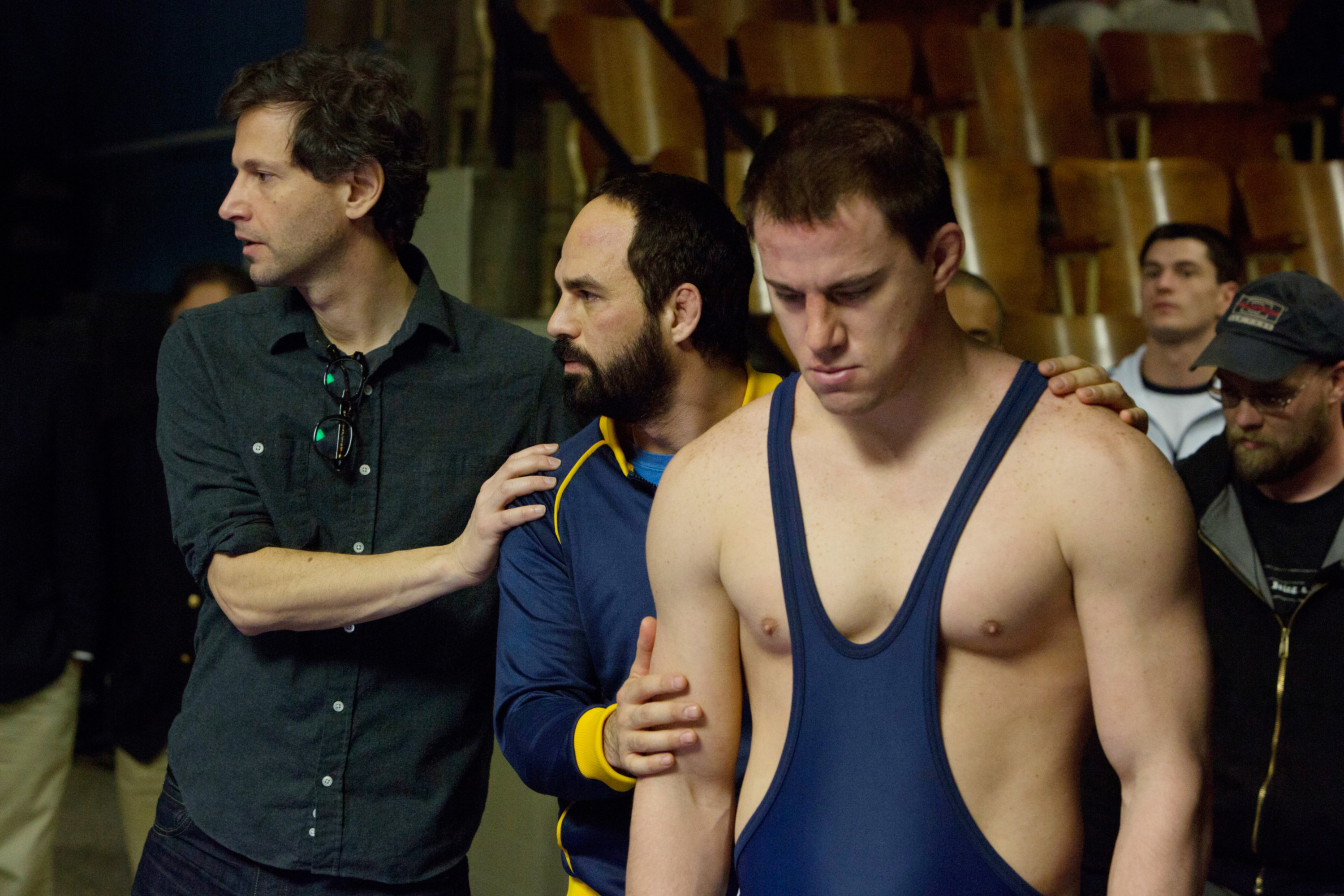 Tatum wearing a wrestling uniform with his coaches behind him