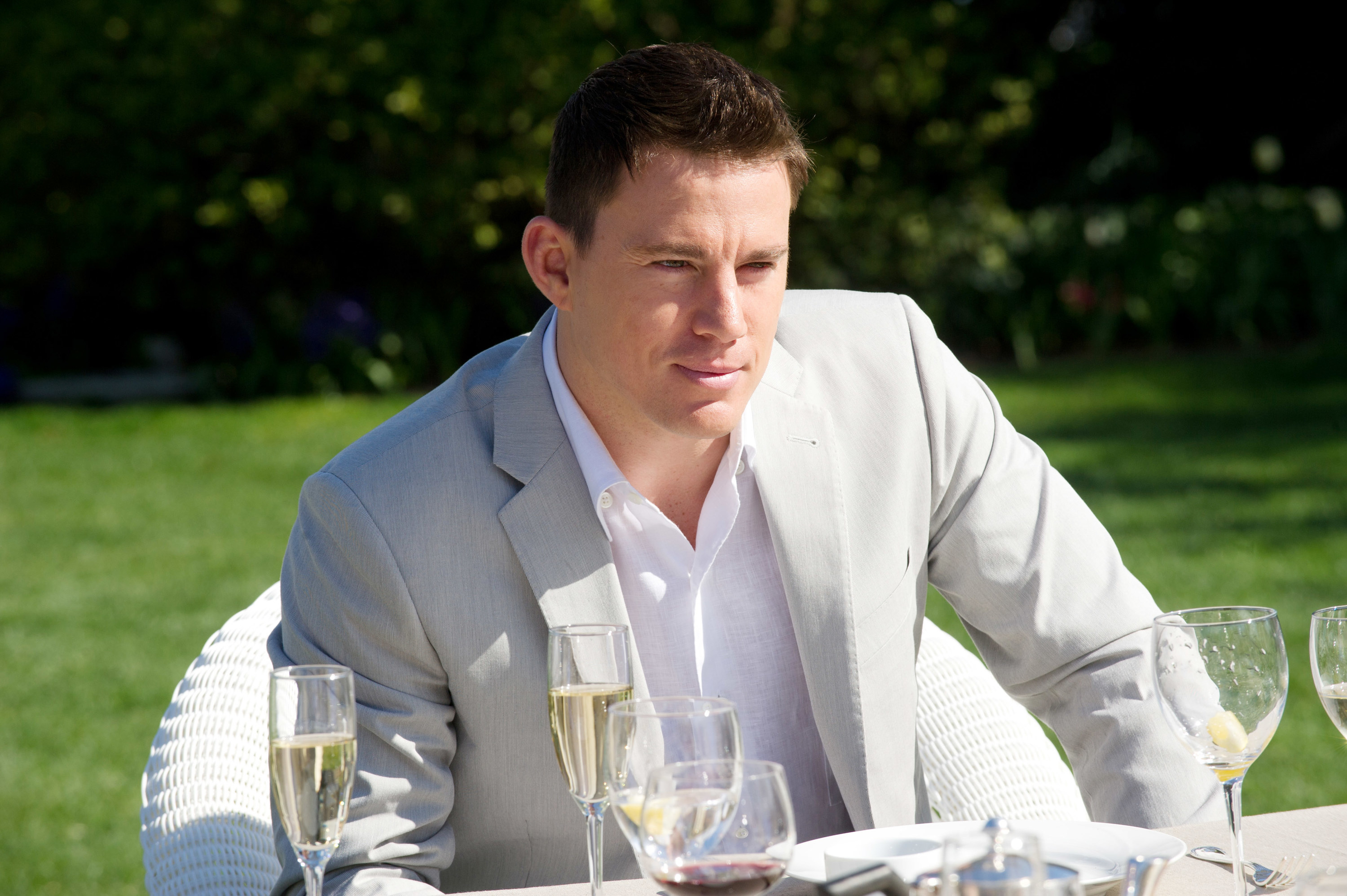 Tatum in a sports coat sitting outside at a table with champagne