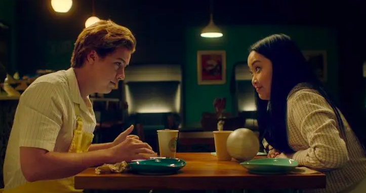Cole Sprouse and Lana Condor sit at a table drinking coffee together