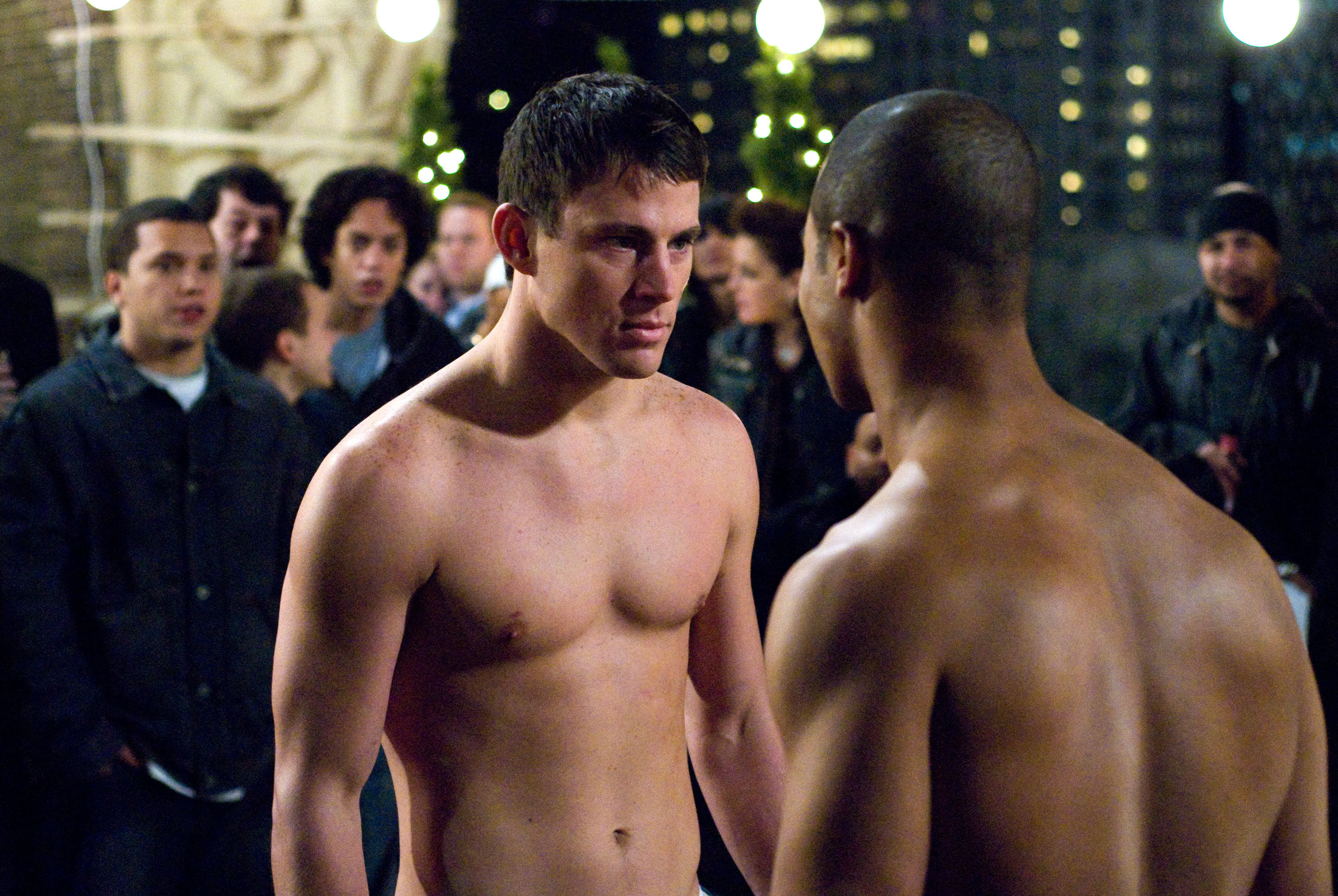 Tatum without a shirt on about to fight someone and onlookers in the background