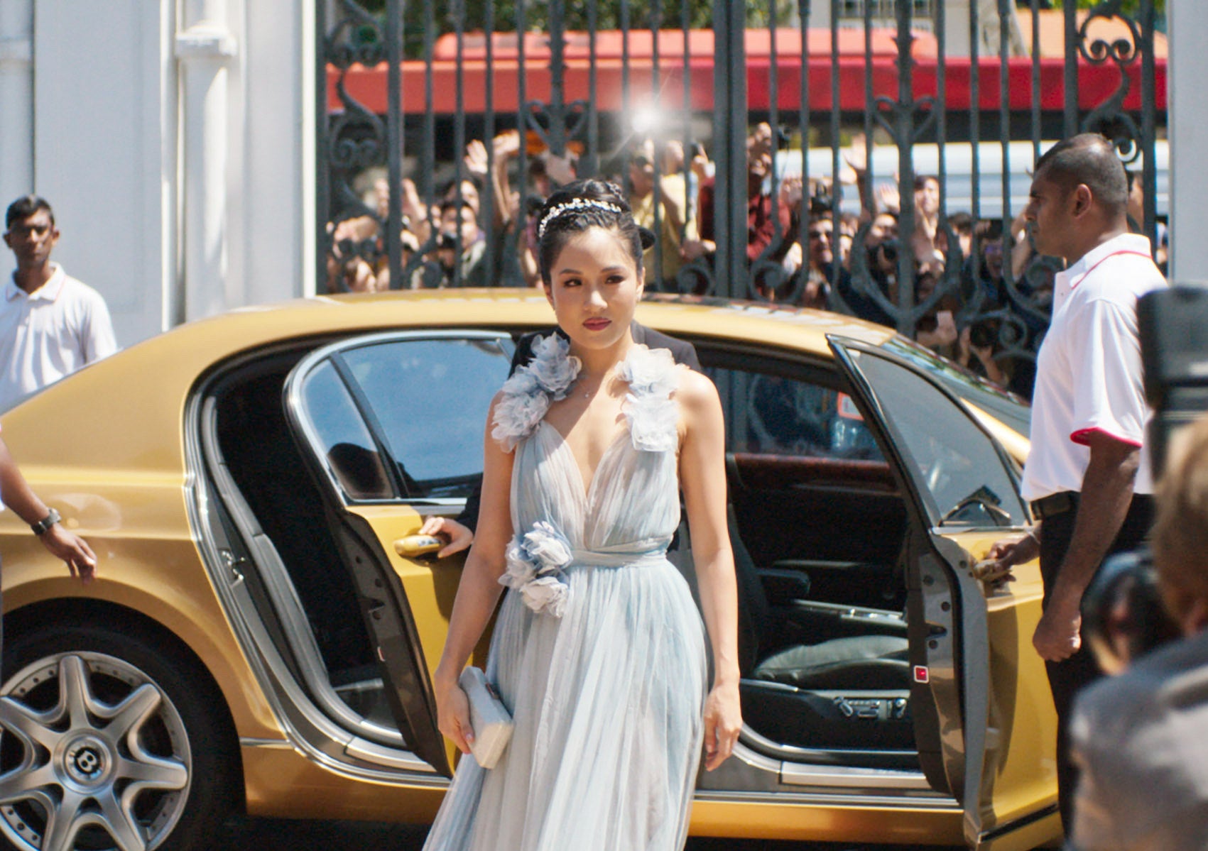 Constance Wu getting out of a gold car in a blue tulle dress