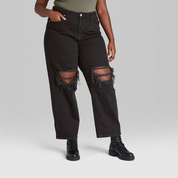 model wearing black jeans with holes/distress fabric around knees