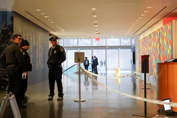 Several police officers stand together near a cordoned-off area inside a lobby