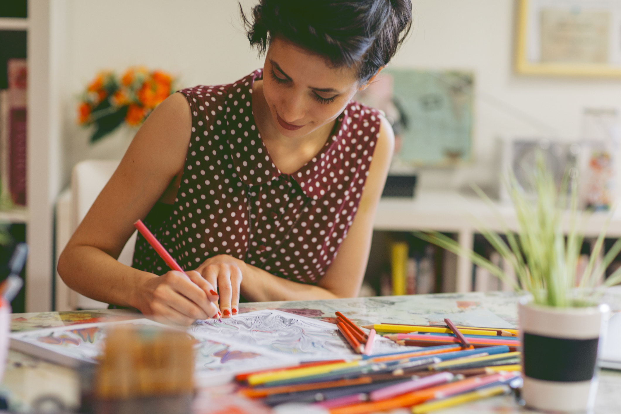 A woman uses colored pencils in a coloring book