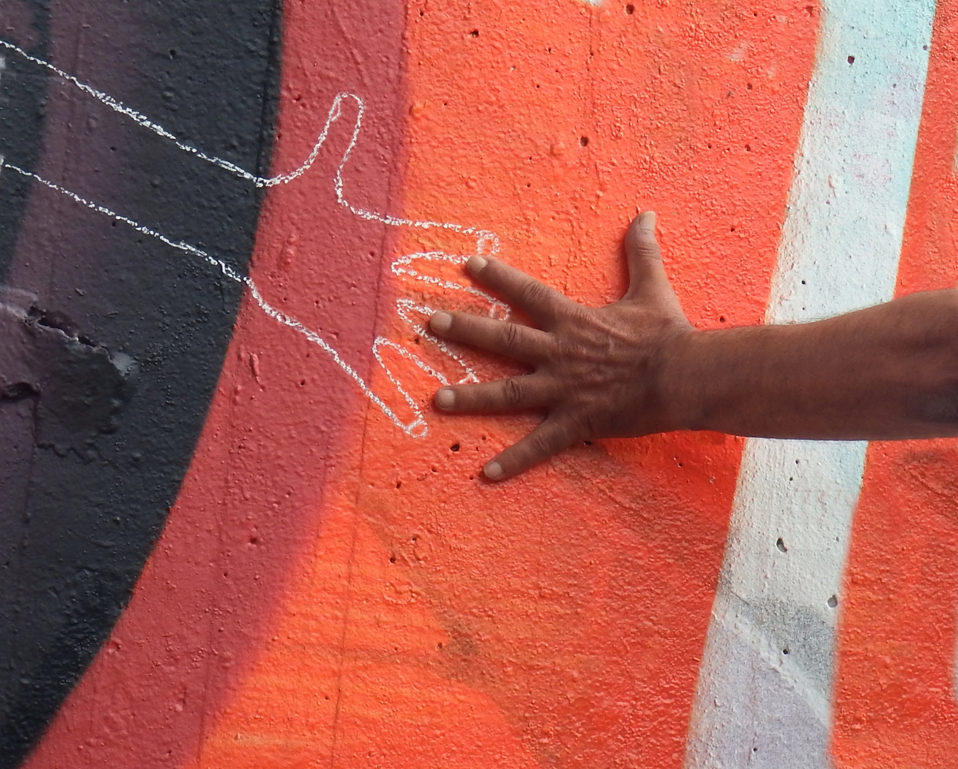 A hand touches a chalk outline of a hand
