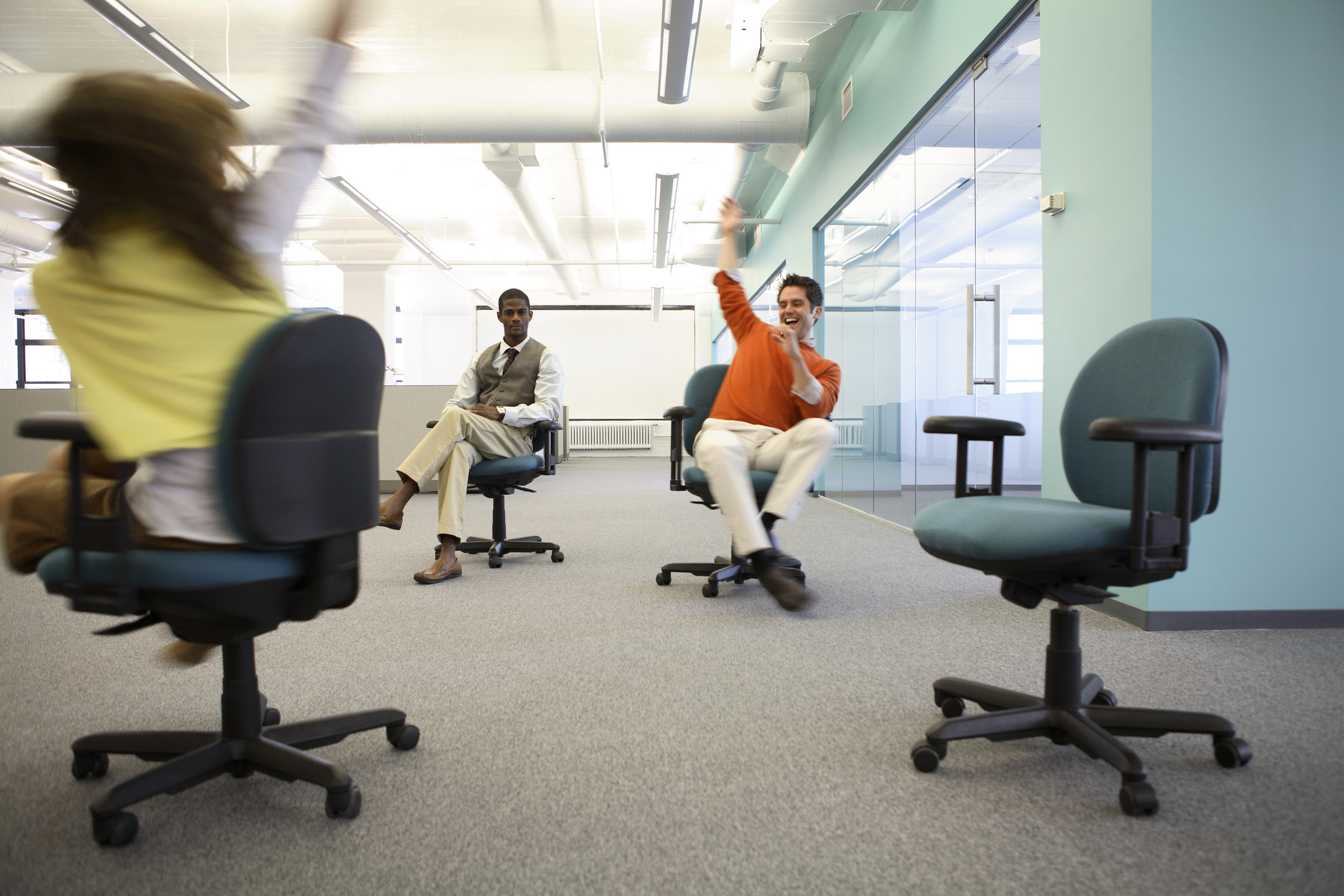 Workers spinning in chairs in office