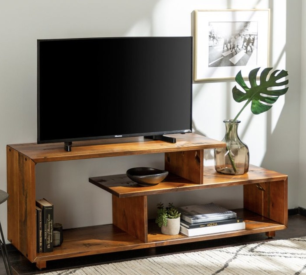 A rustic wooden television stand with storage for books.