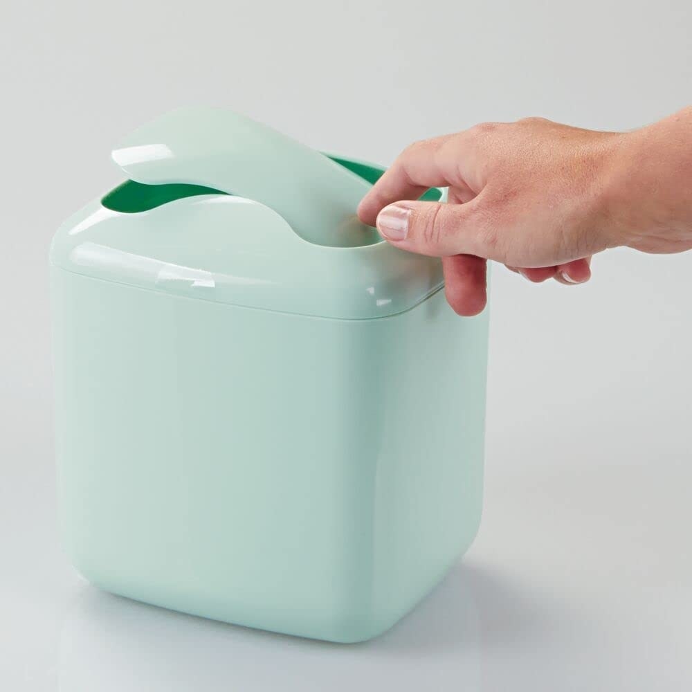 the mint green mini trash can with a finger pushing the lid open