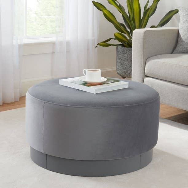 a round gray ottoman in a living room