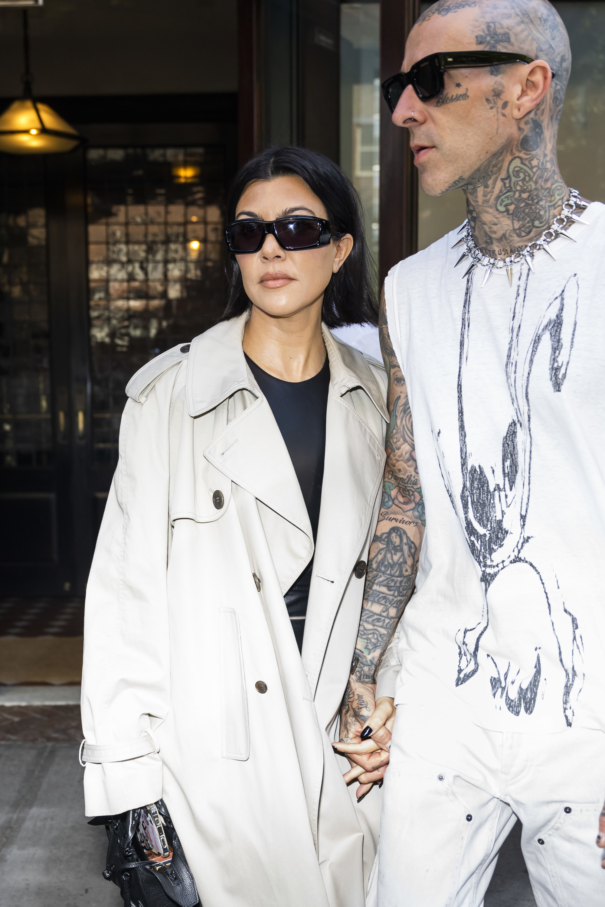 Kourtney and Travis holding hands as they leave a building