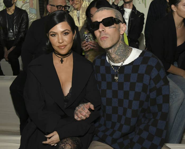 Kourtney and Travis sitting with their arms locked at an event