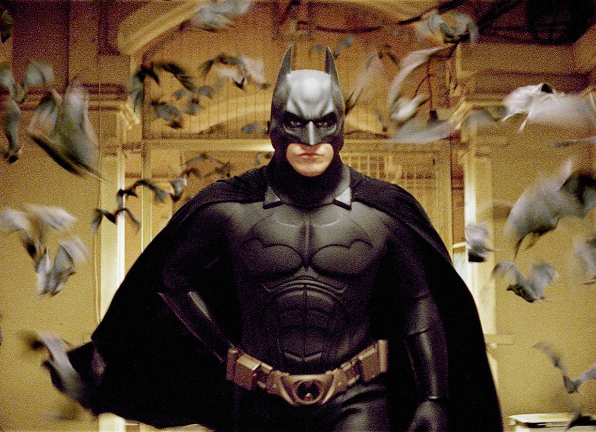 Christian Bale dressed as Batman surrounded by flying bats