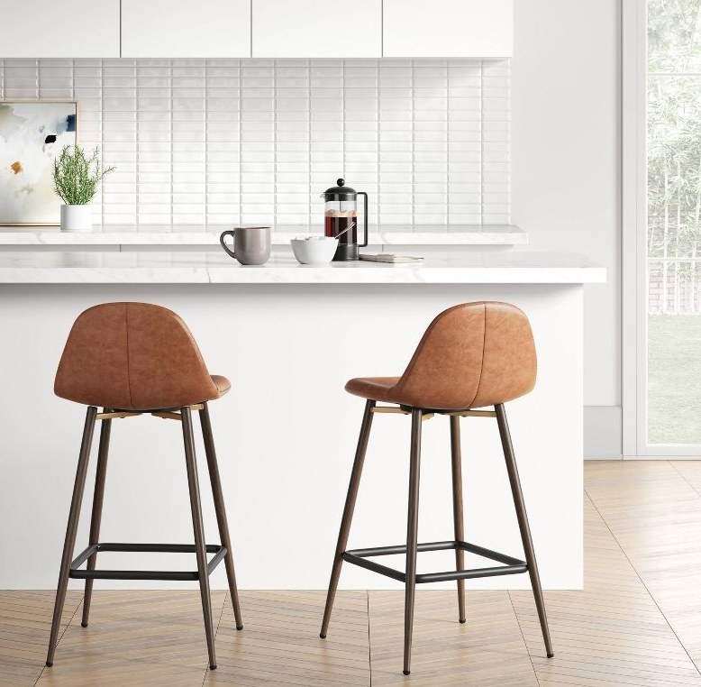 A caramel faux leather upholstered bar stool