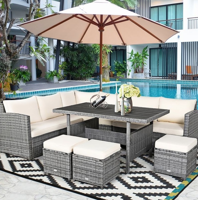 A 7 piece patio rattan set with white cushions next to a pool