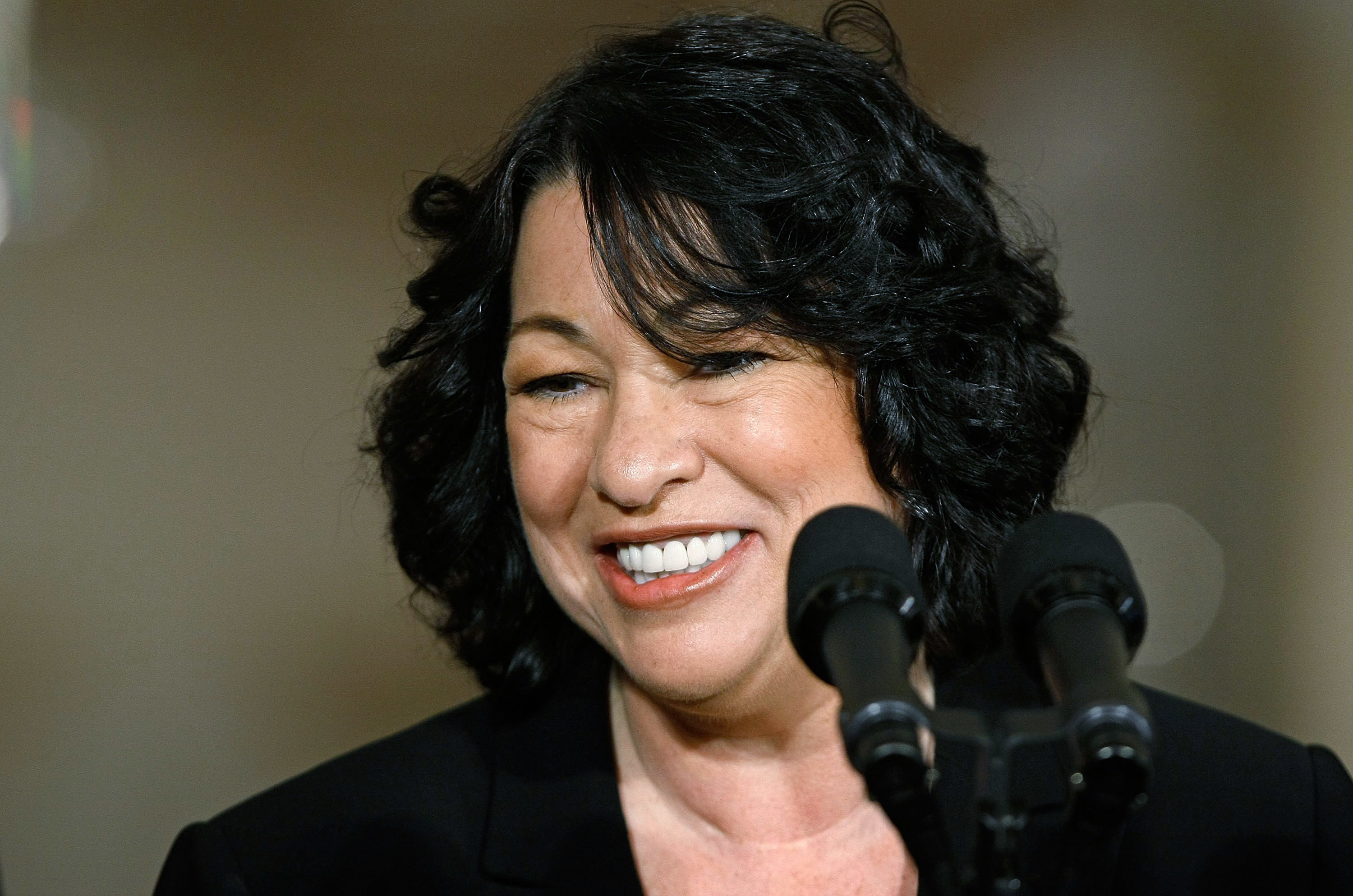 Sonia Sotomayor smiling, with a microphone in front of her