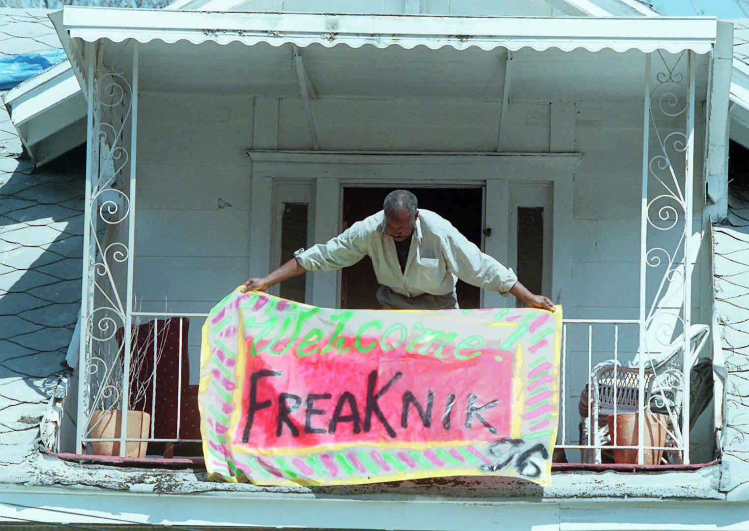 A man hangs a welcome freaknik 96 flag from a balcony