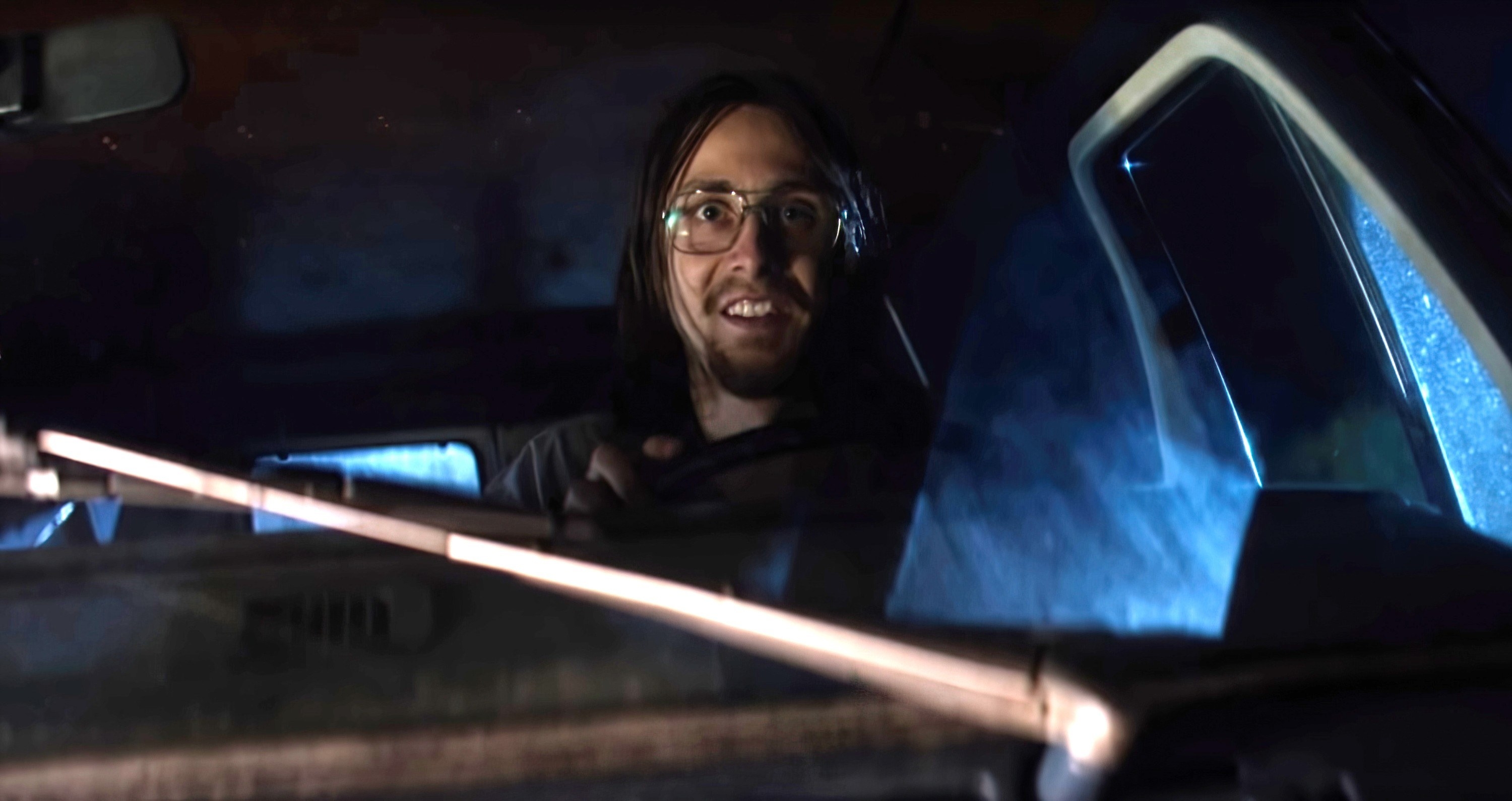 A man sitting in the driver&#x27;s seat of the van looking out the front window at something, shocked