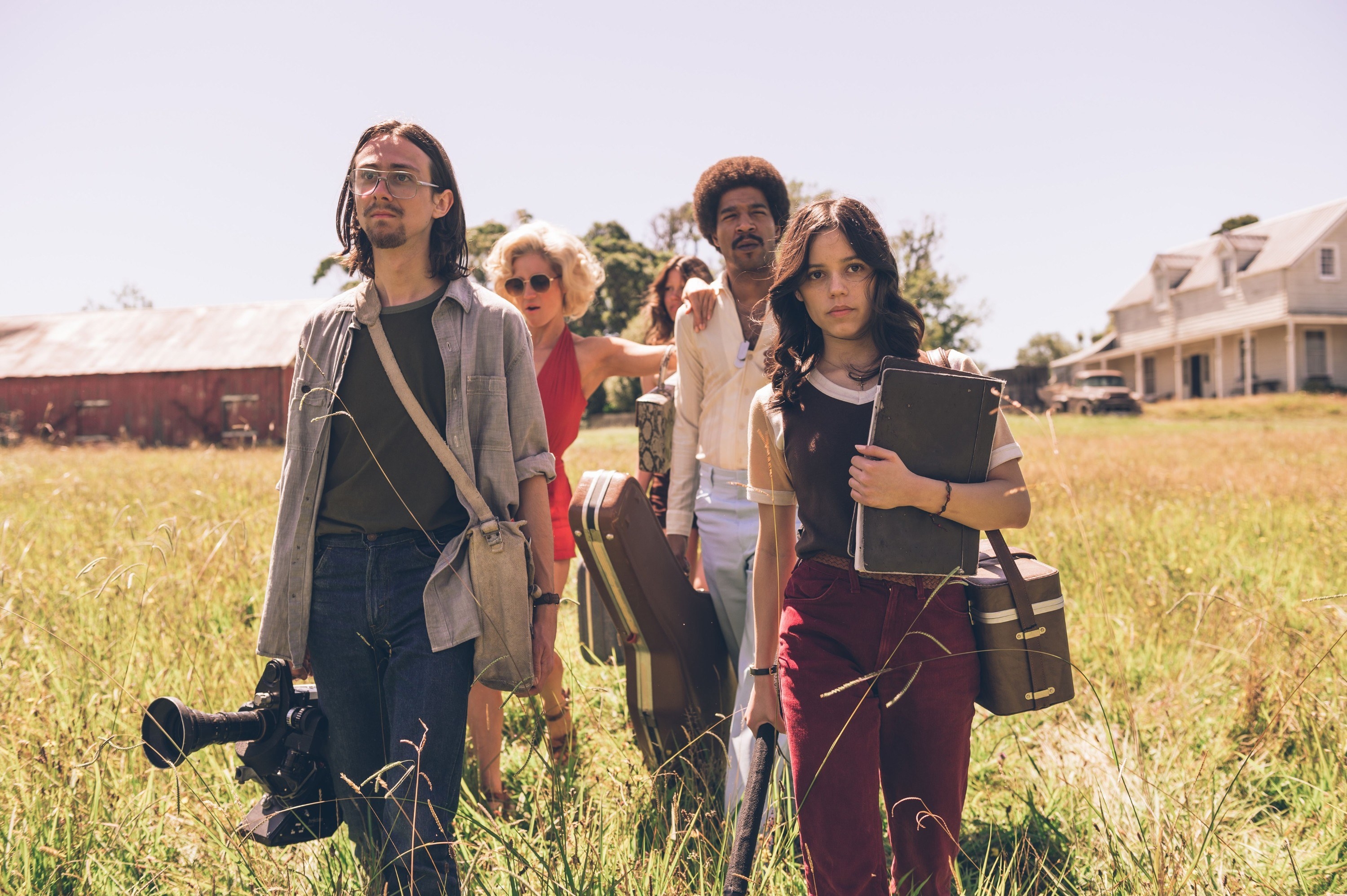 The group walking through a field, carrying their equipment