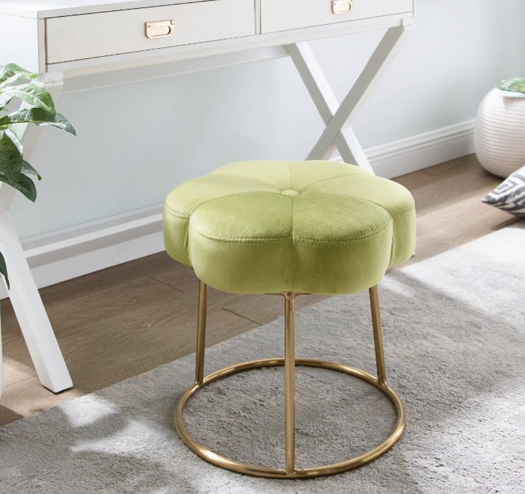 A green chair with a floral design and gold base.