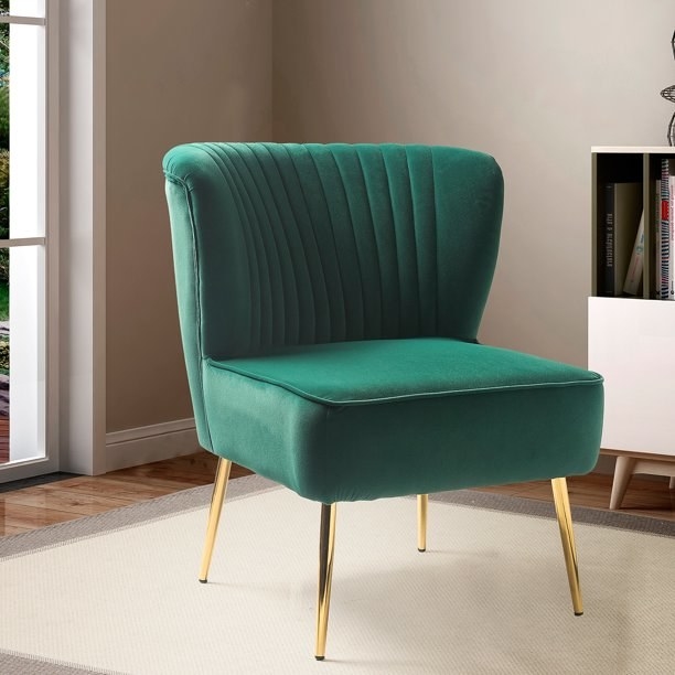 A green velvet armless chair with gold legs