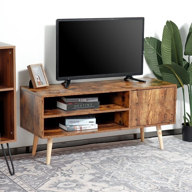 a brown wooden entertainment center decorated with books and a television on top
