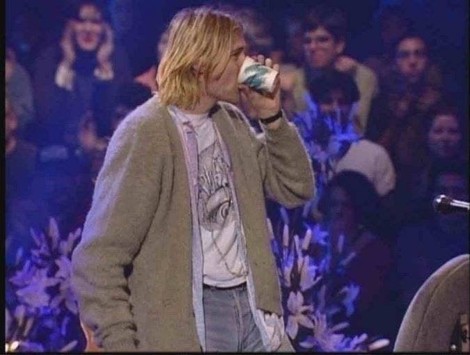 Kurt Cobain standing up and drinking from cup