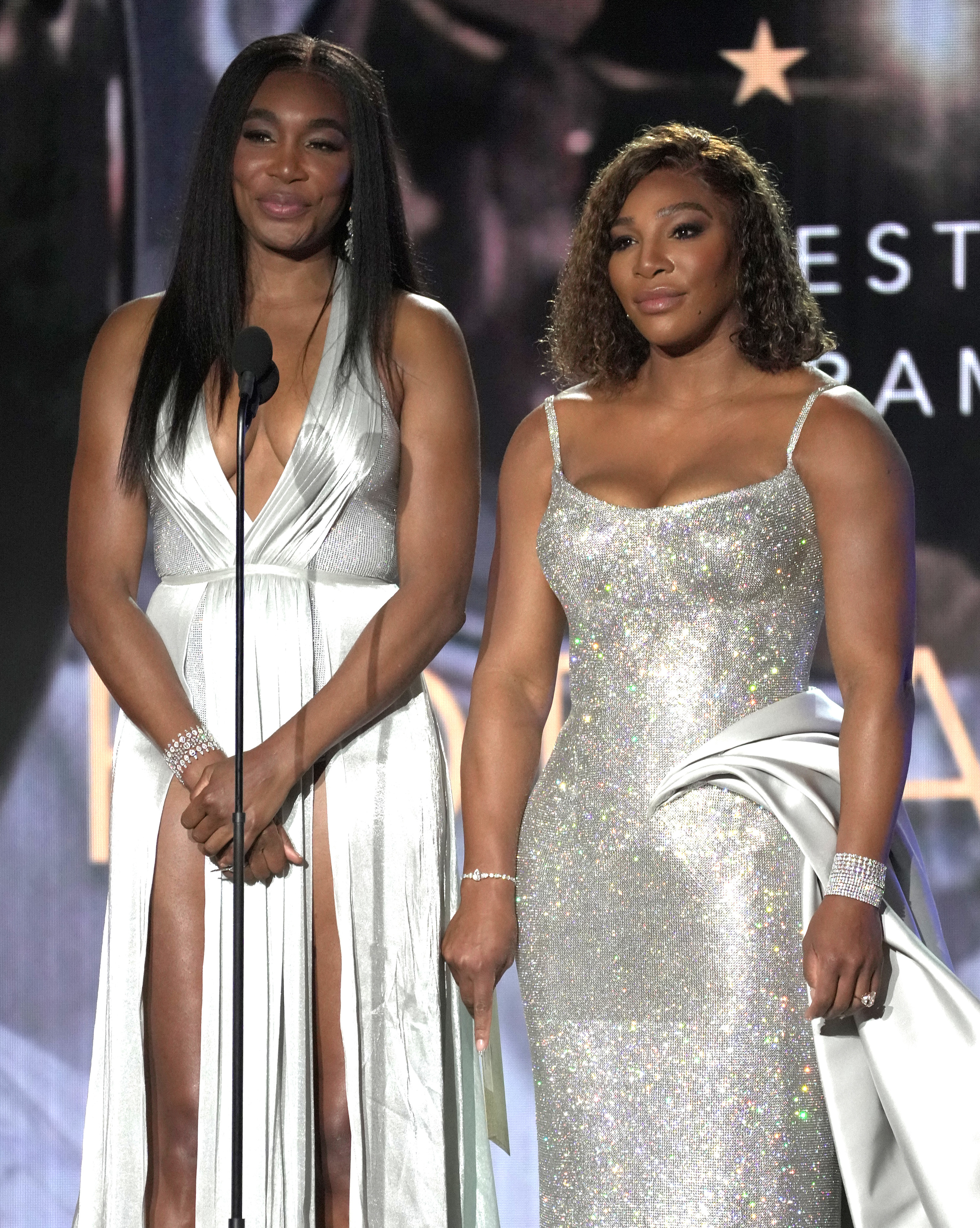 Serena and Venus stand in front of a microphone