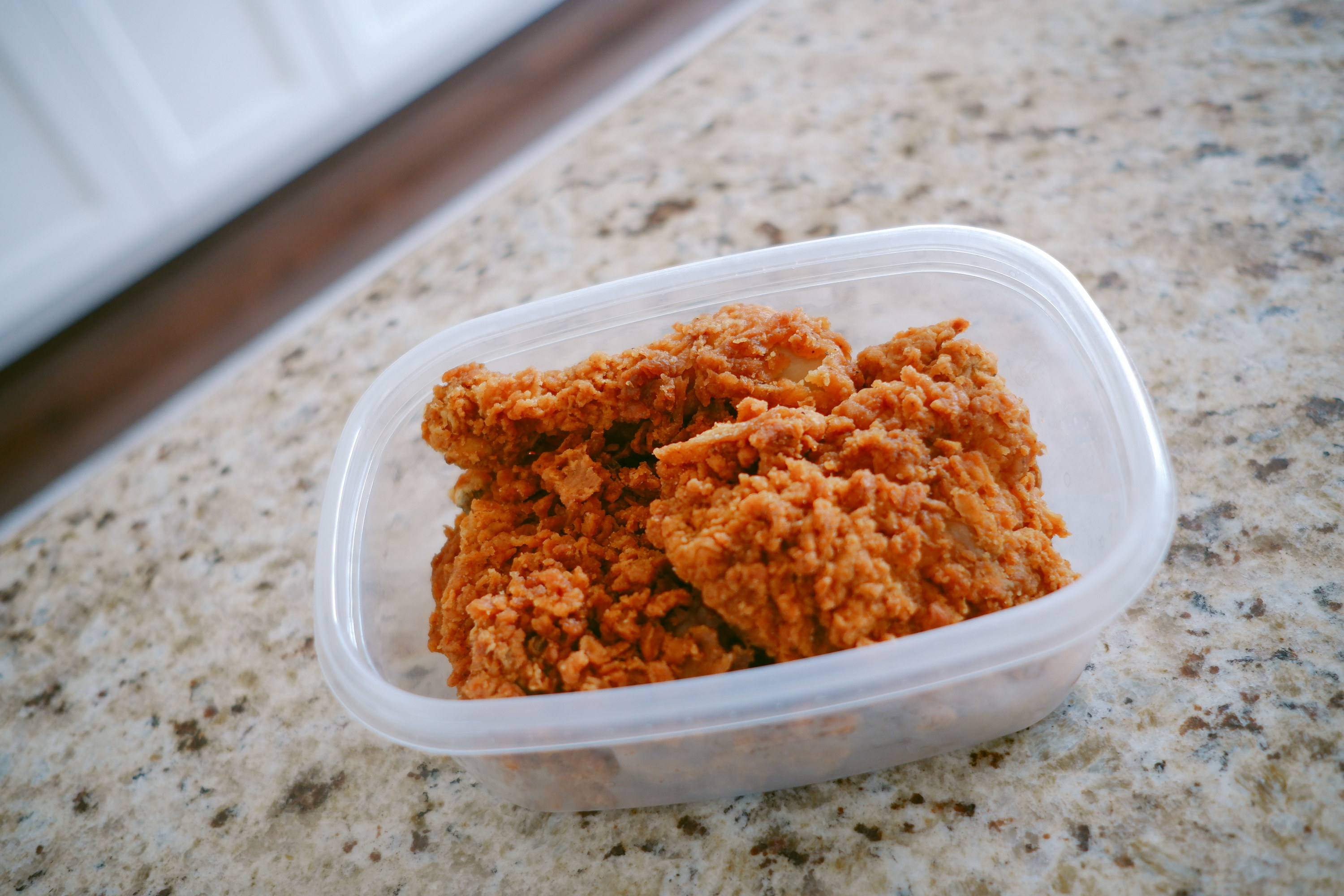 leftover fried cold chicken in a plastic tupperware container