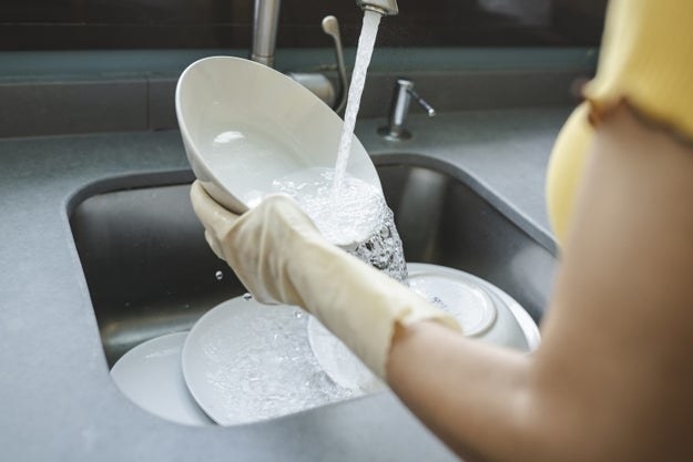 Rinsing a dish with water in the sink