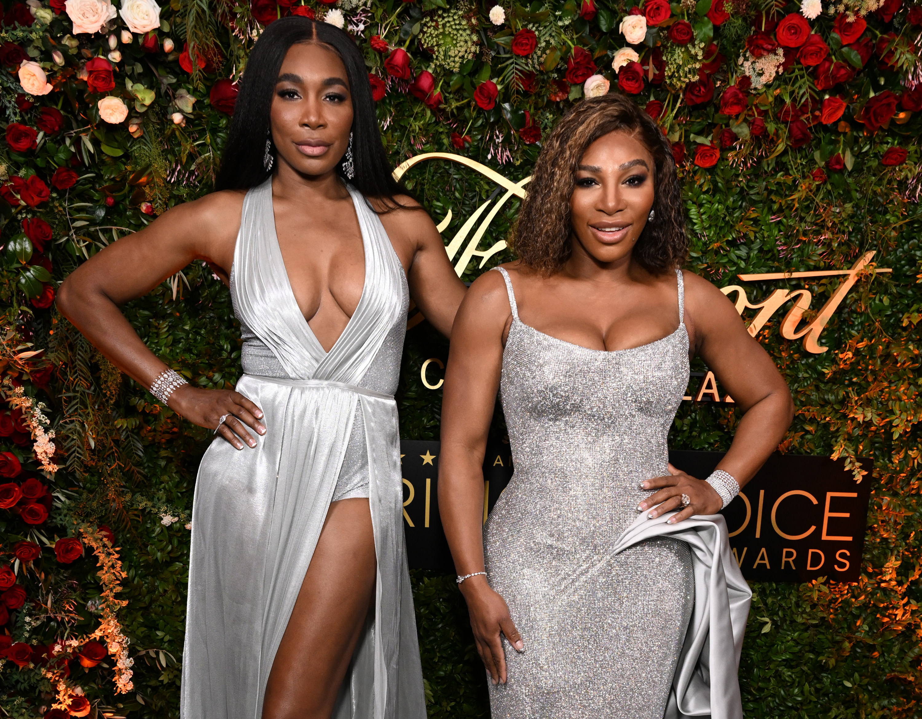 Venus and Serena Williams pose for a photo in front of roses