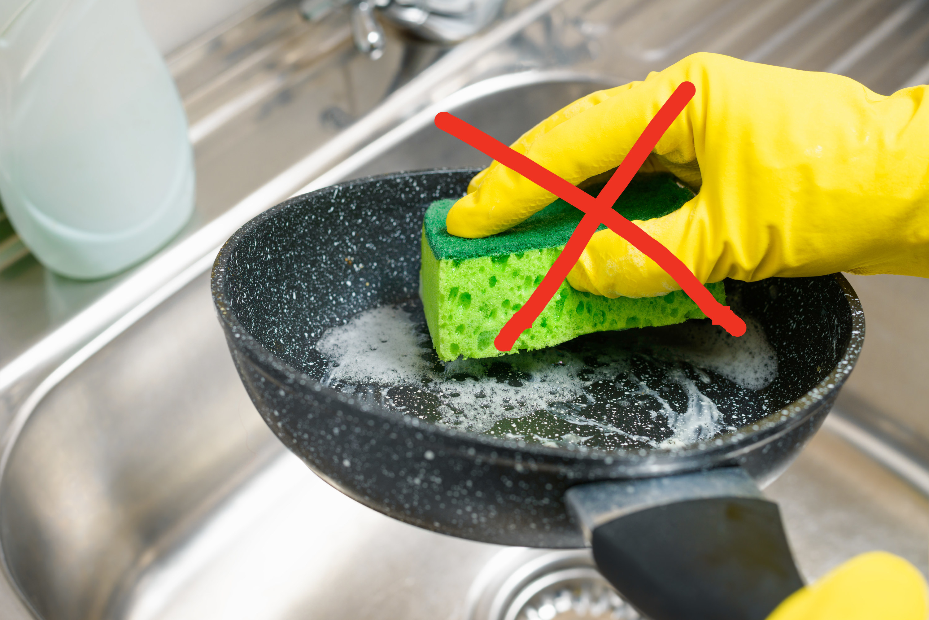 an X through someone washing a nonstick skillet with soap and a sponge