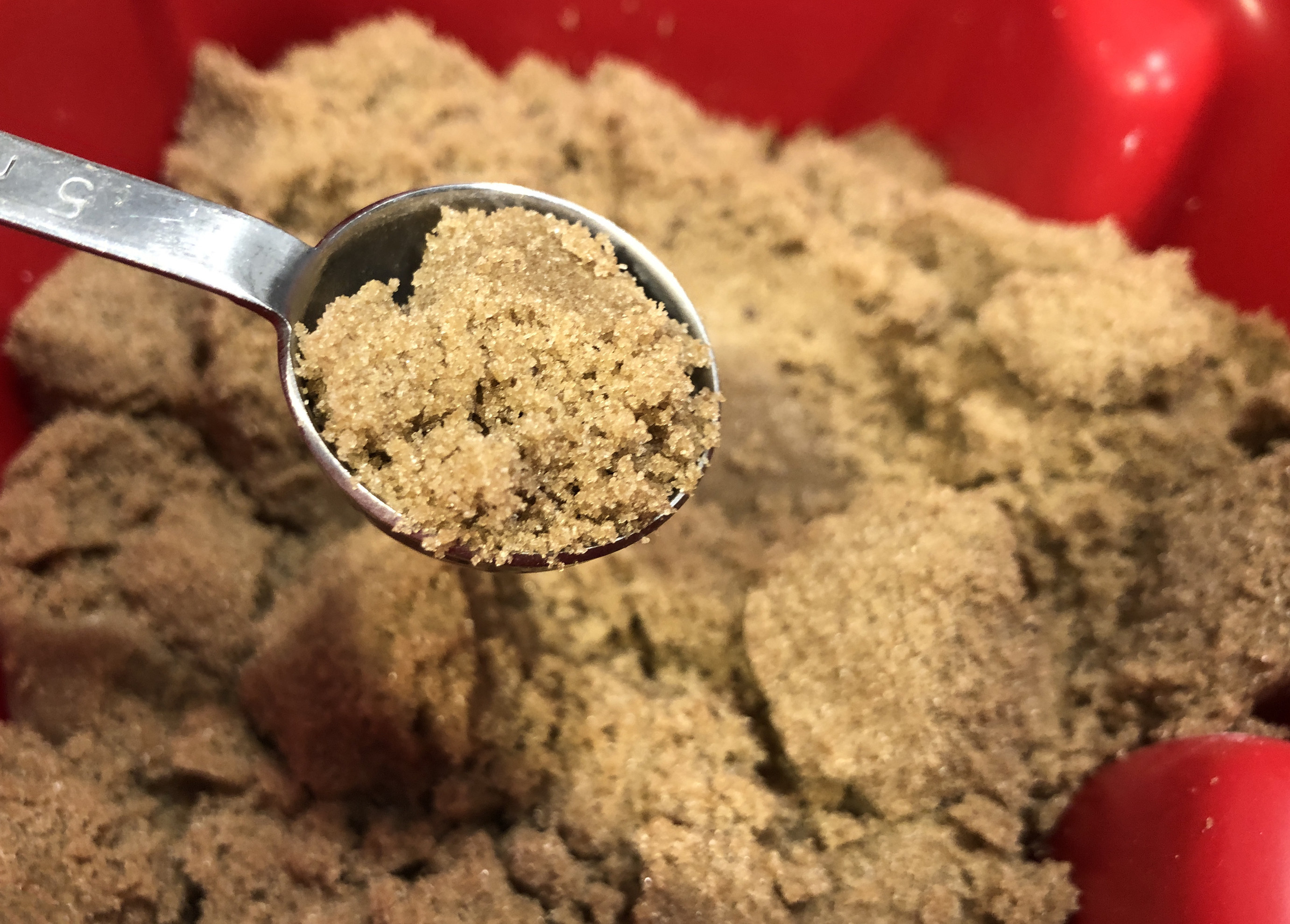 Scooping up brown sugar in a measuring spoon