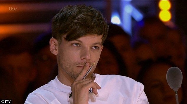 Louis Tomlinson with a judgemental look, holding a pen.