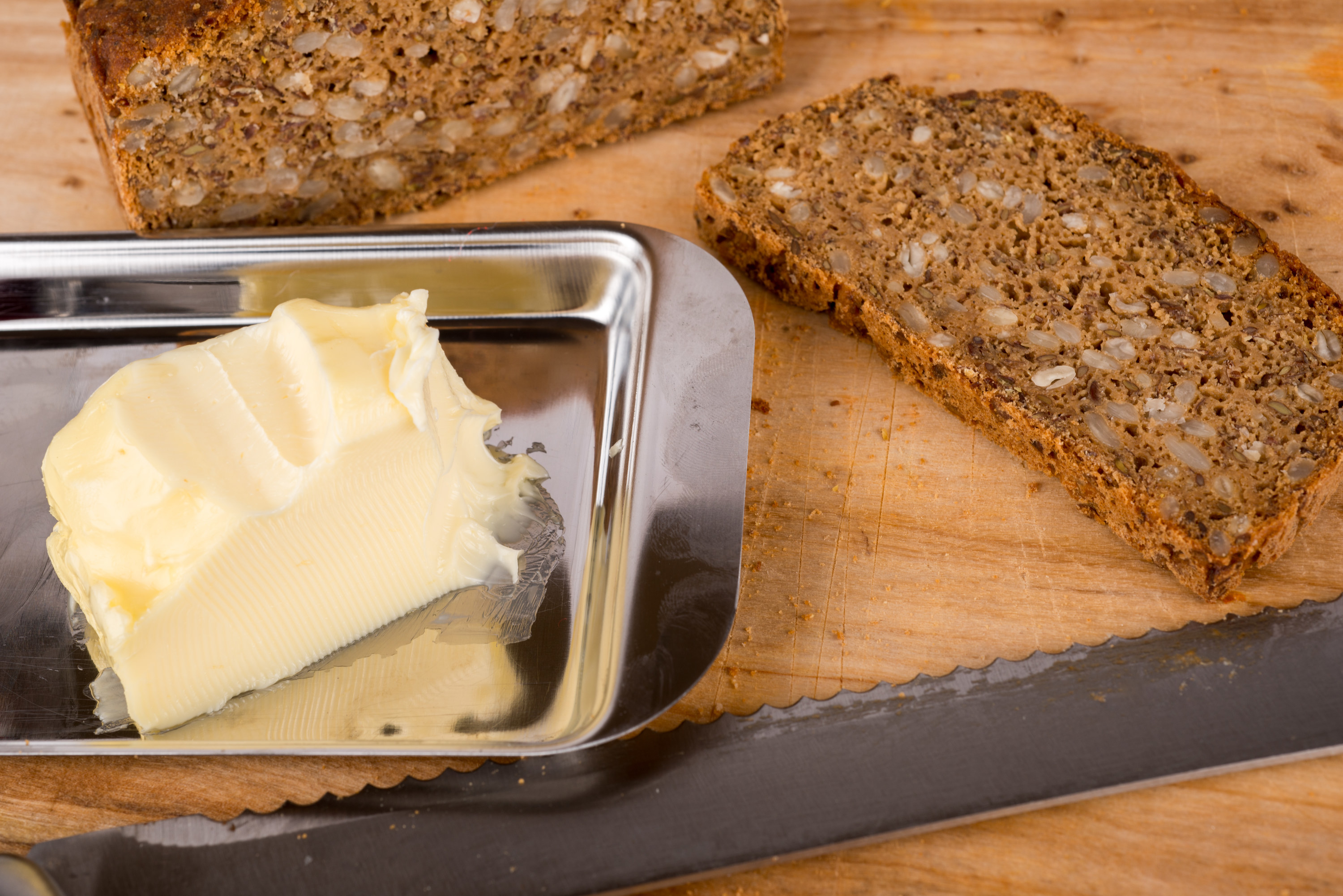 Room temperature butter in a dish next to a slice of bread