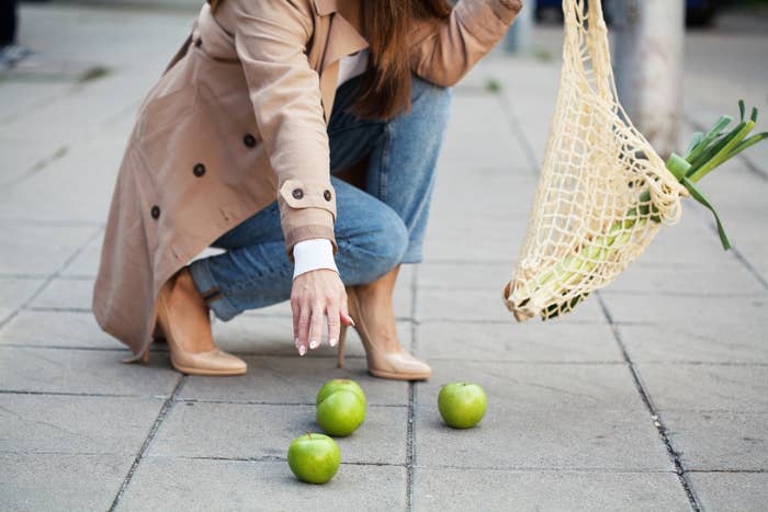 Picking up apples that fell in the middle of the street sidewalk