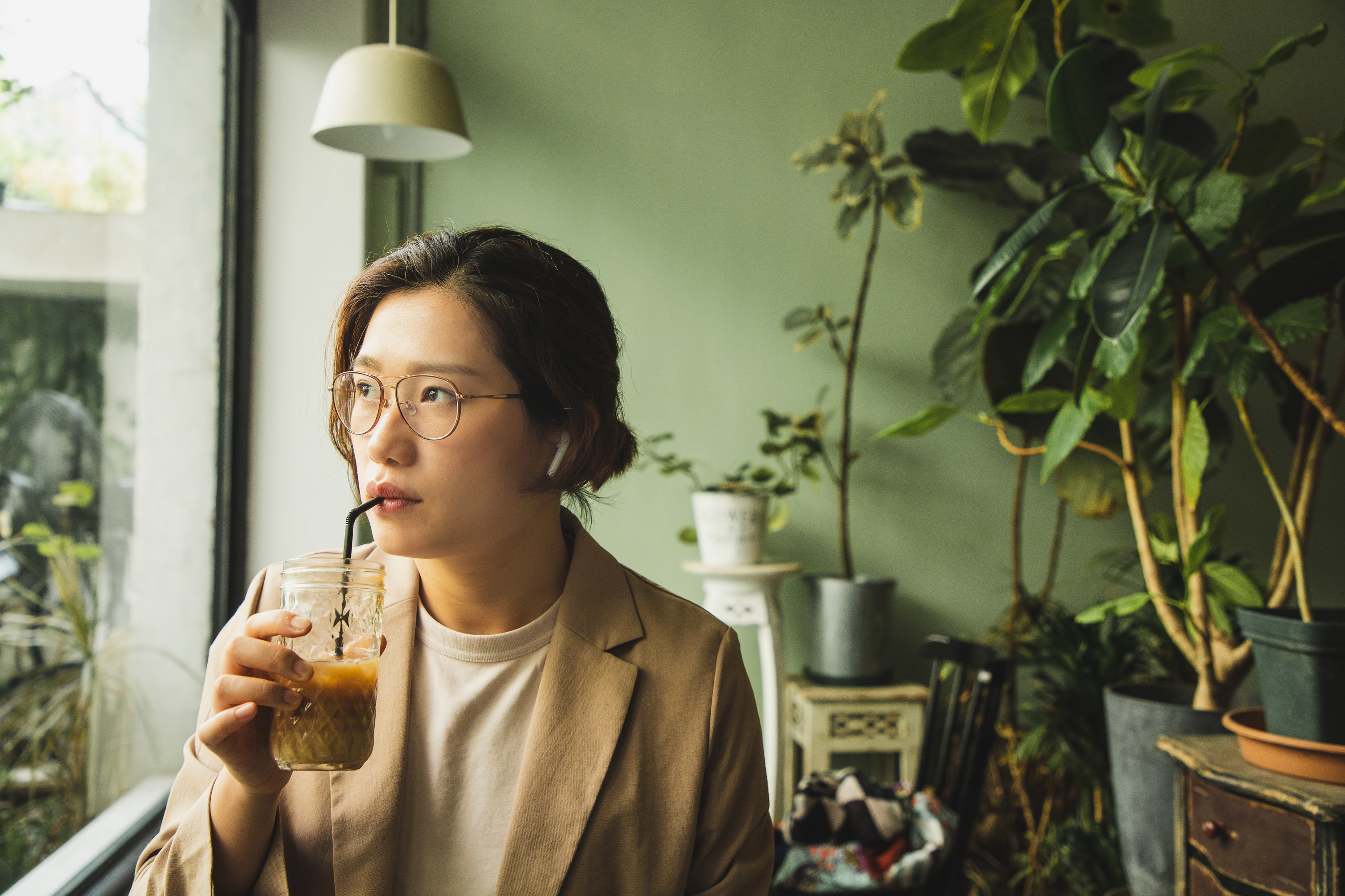 Woman drinking iced coffee while looking out of a window