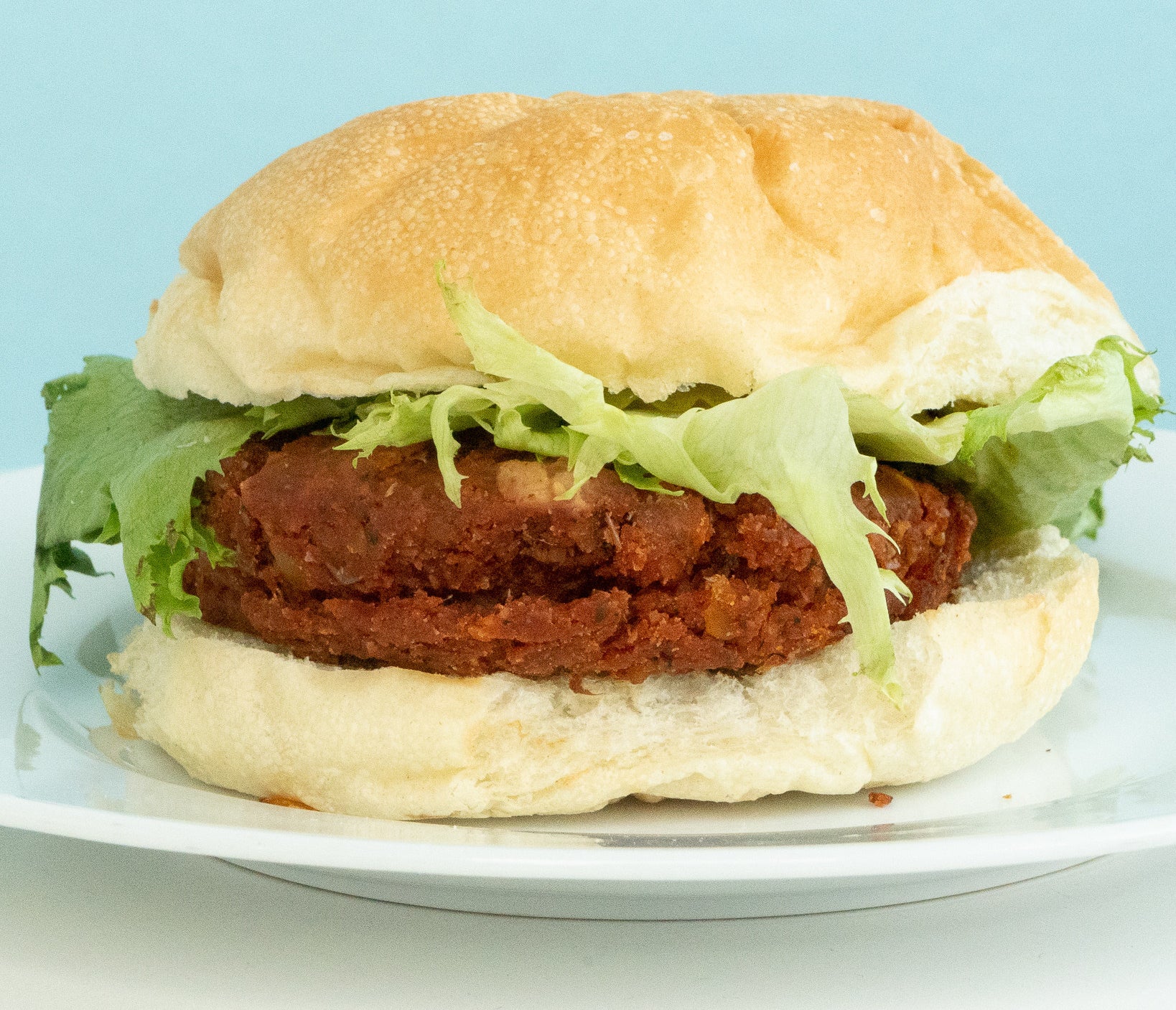 a burger with a reddish patty with lentils and corn visibly exposed