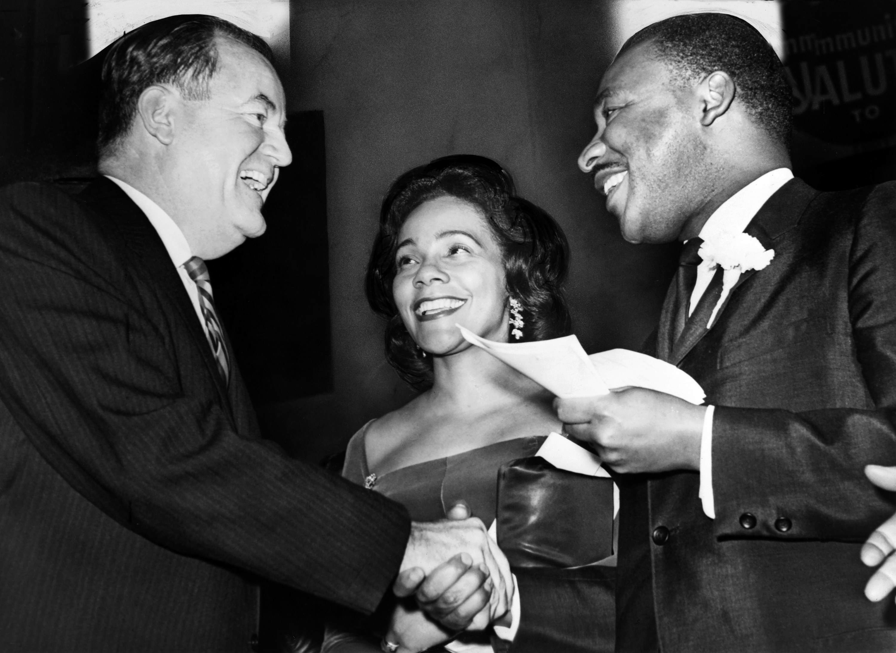 U.S. Vice President-elect Hubert Humphrey shaking hands with Dr. King, as Mrs. King looks on smiling