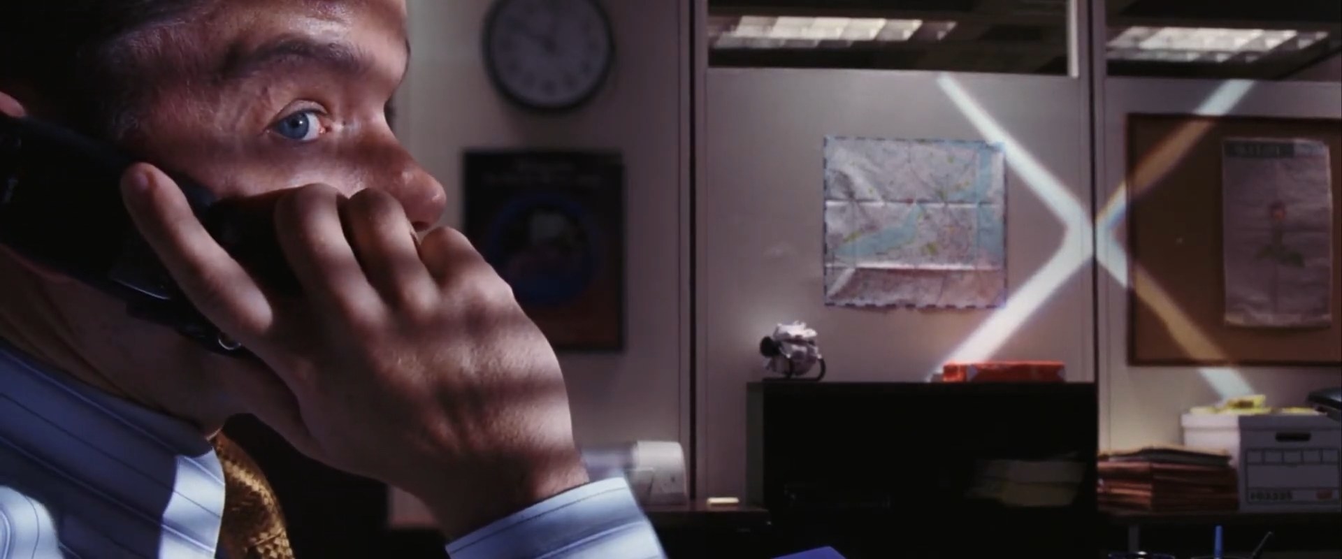 A man on the phone with a &quot;X&quot; shining onto the wall next to him in &quot;The Departed&quot;