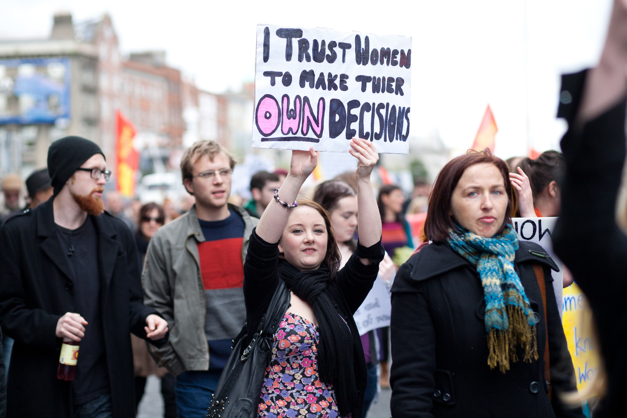 A woman holding up a sign at a protest for abortion rights that reads, &quot;I trust women to make their own decisions.&quot;