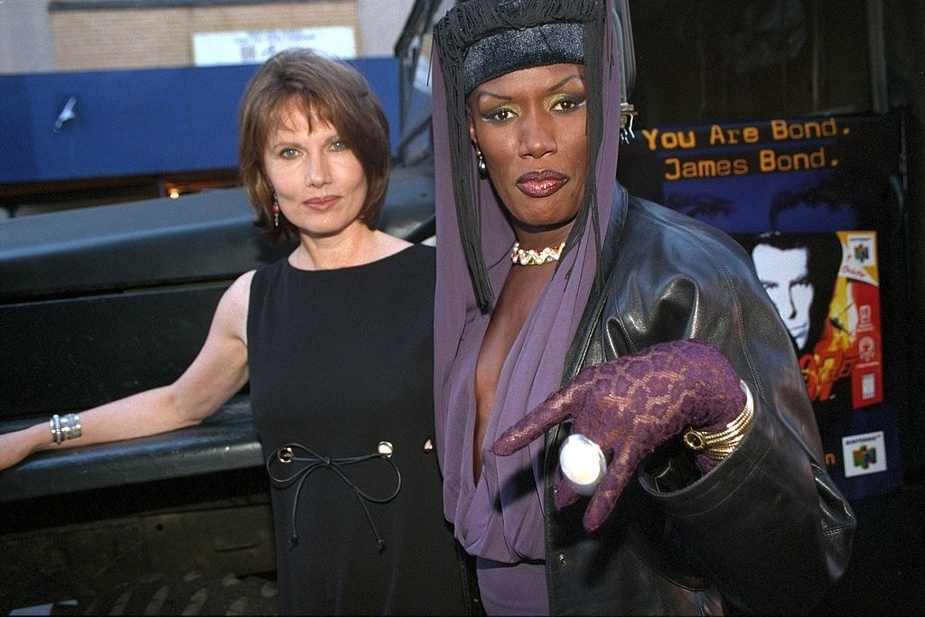 Maud Adams and Grace Jones standing in front of truck with a poster of the game on it