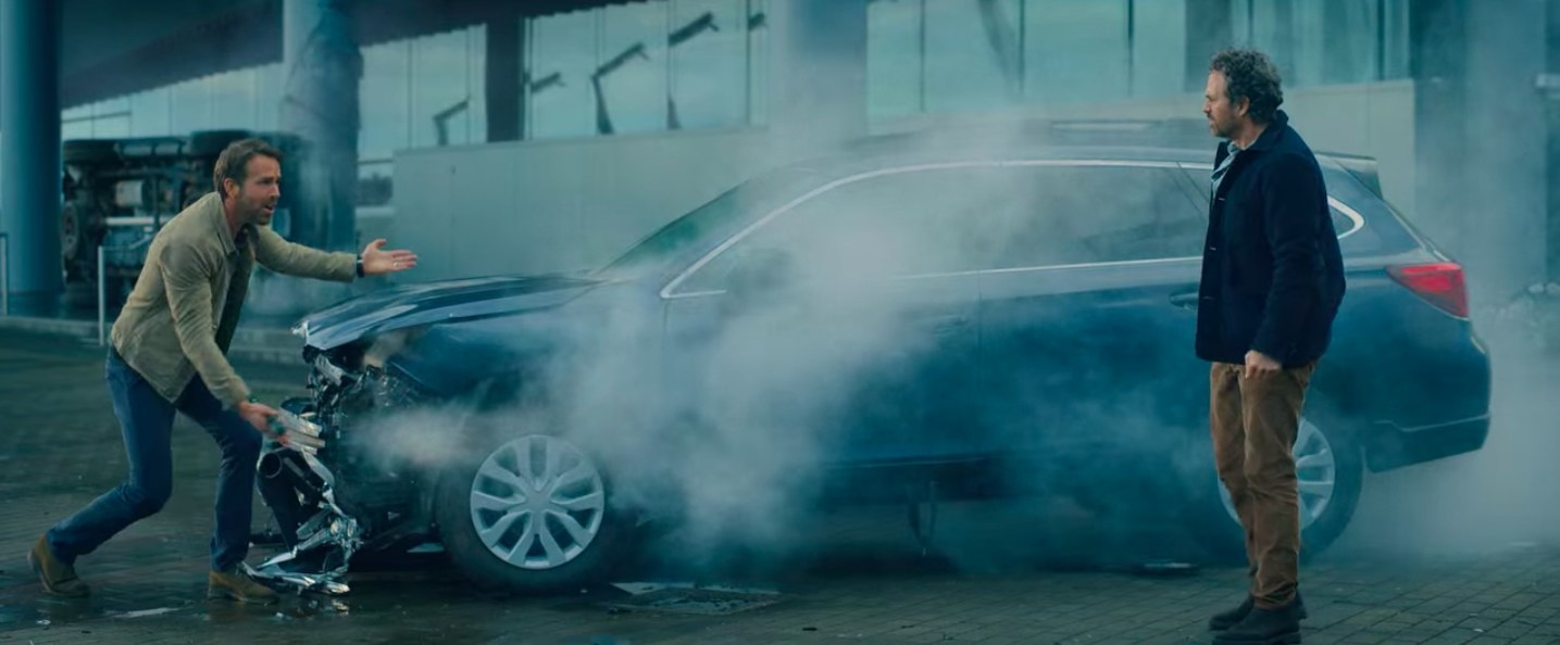 Adult Adam and Louis standing next to a wrecked Subaru in &quot;The Adam Project&quot;