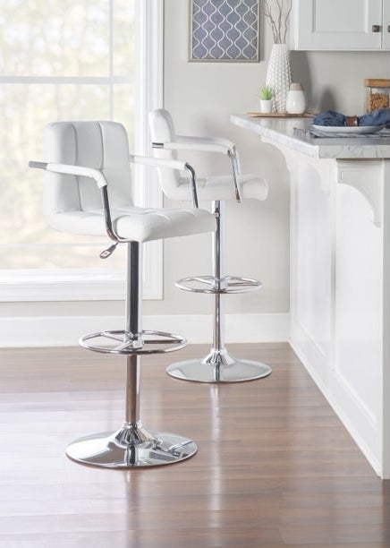 two adjustable white quilted bar stools at a kitchen bar