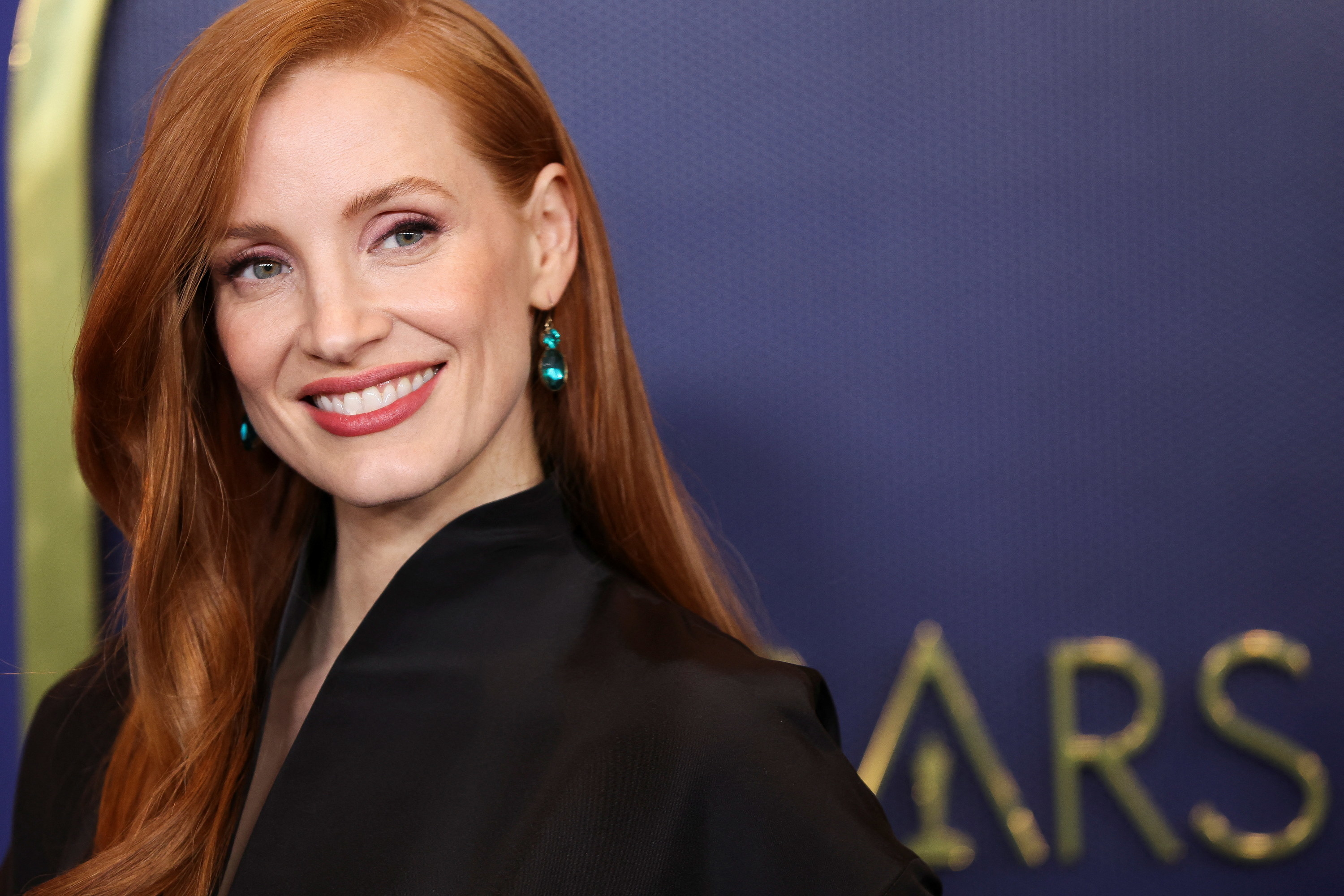 Jessica Chastain and large earrings smiling at something off camera