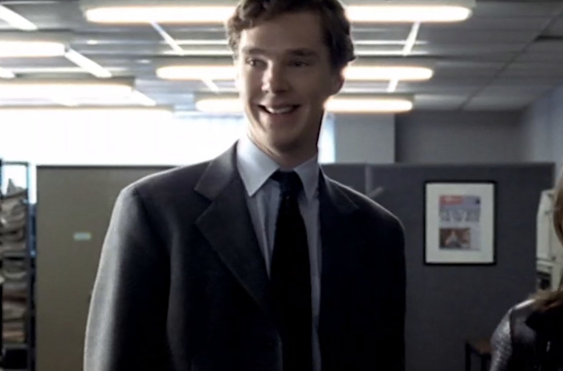 A young Benedict Cumberbatch wearing a suit and tie and smiling