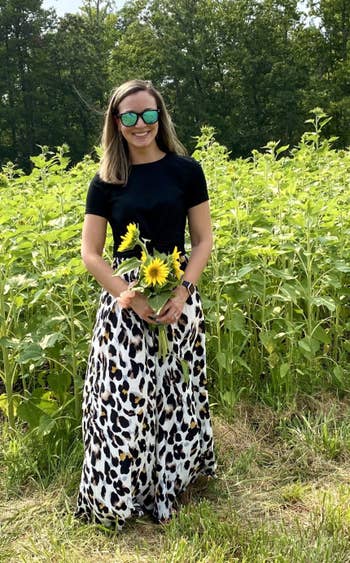 a reviewer wearing the skirt in leopard while holding flowers