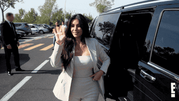 Kim Kardashian getting out of a car and waving at fans
