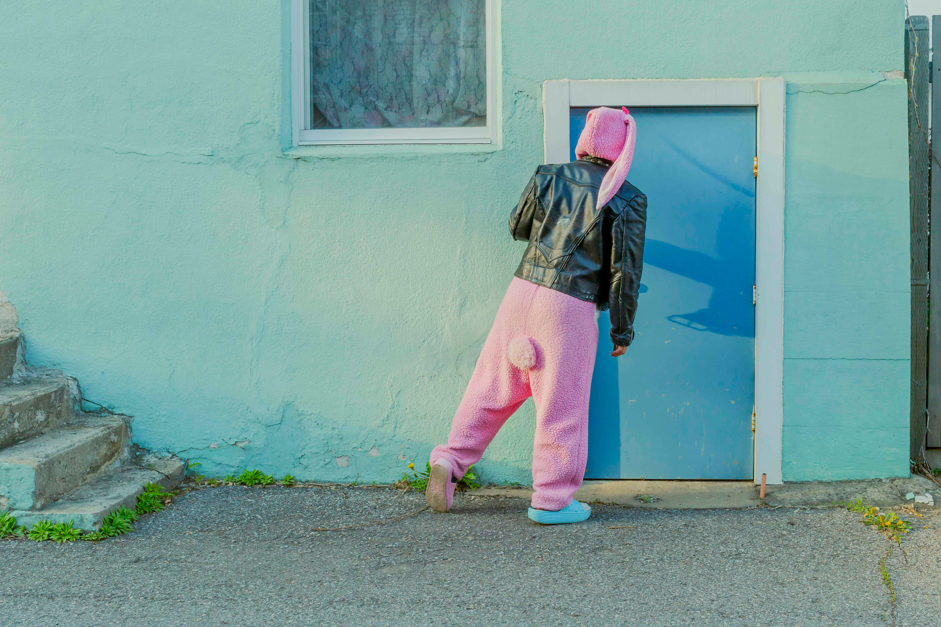 A person in a bunny costume wearing a leather jacket looking at a closed door