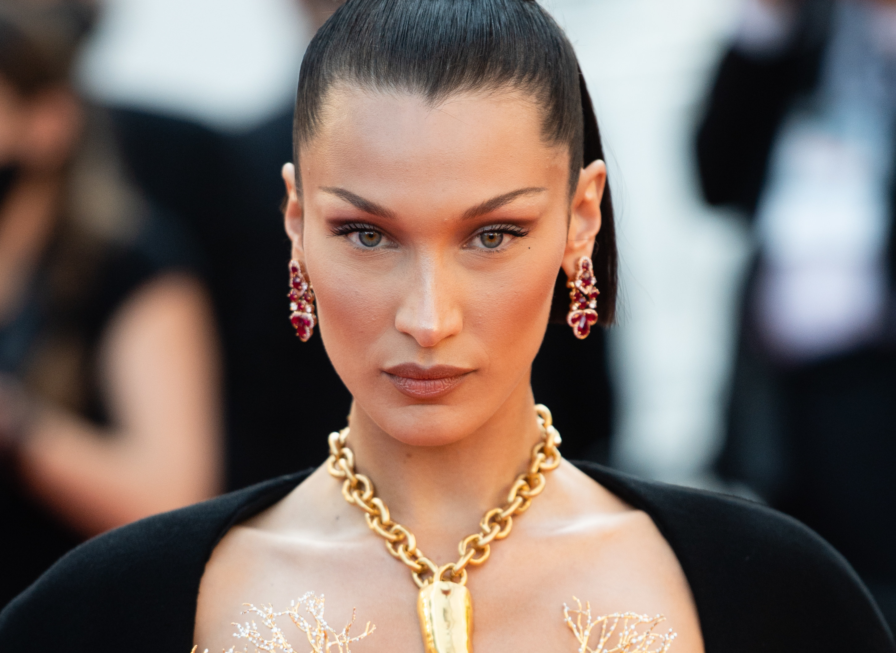 A close-up of Bella Hadid wearing ruby earrings and a gold necklace