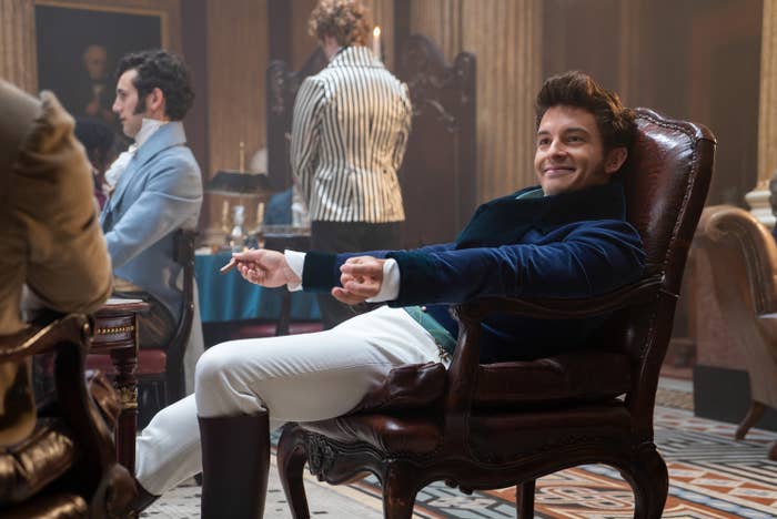 Jonathan sitting in a chair  in a scene from Bridgerton